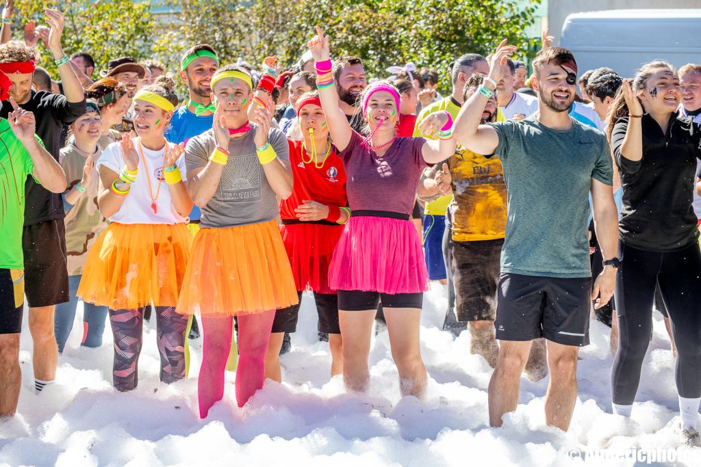 Des participants les bras en l'air dans la mousse blanche du village d'arrivée